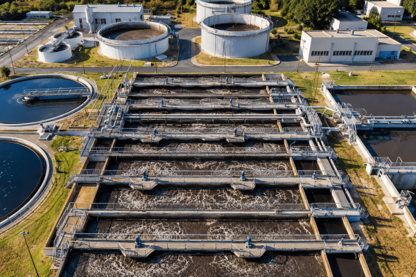 Vista aérea de uma estação de tratamento de esgoto com tanques de aeração, decantadores, tubulações e estruturas de processo.